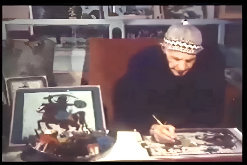 Muhammad Harb (Abou Sobhi Al-Tinawi) painting at his desk in Damascus